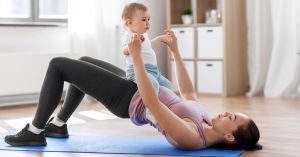 Woman doing a yoga pose with her baby and smiling